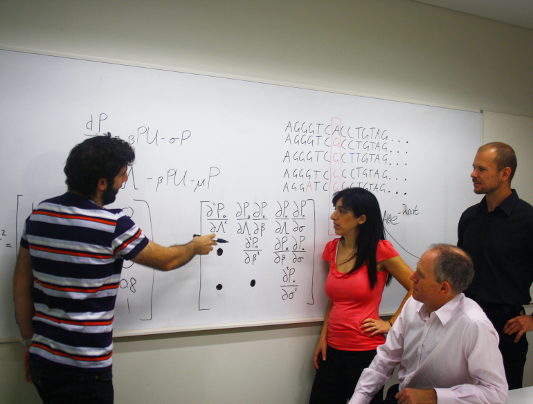 Group of mathematicians meeting, looking at maths formulas on whiteboard.