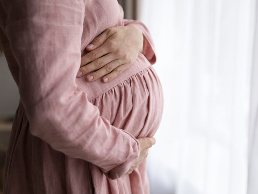 Pregnant woman holds her bump. Credit Shutterstock/fizkes